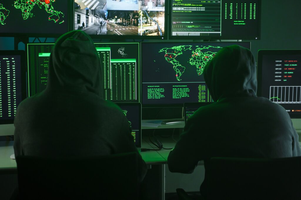 Team of Computer hackers coding on keyboard hidden in illegal hideout full of monitors